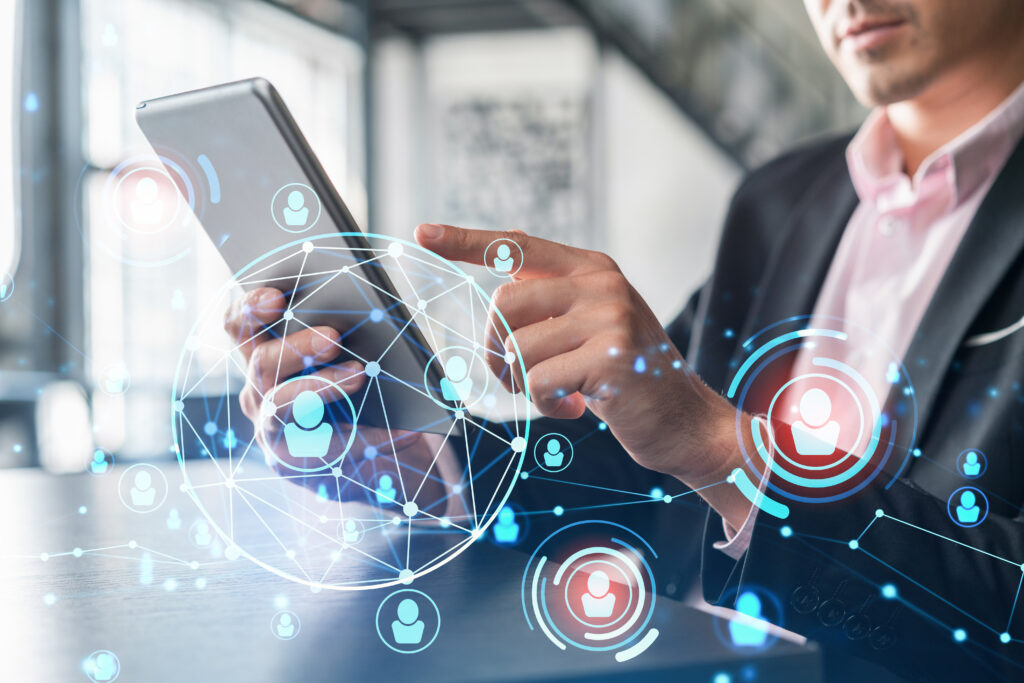 Mann im Anzug bedient ein Tablet, umgeben von digitalen Netzwerk-Symbolen mit vernetzten Personenicons